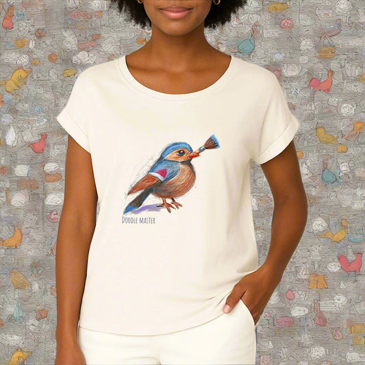 A woman wearing an ivory colored t-shirt with cuffed sleeves. On the fron is a pencil drawing of a little bird, holding a paint brush and the text doodle master. By Rosenmay Studio